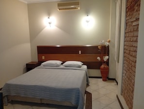 Ein Schlafzimmer mit einem Bett, Nachttischen, einer Vase mit Blumen und zwei Wandleuchten.