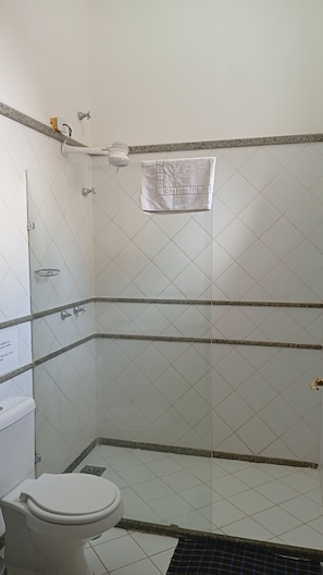 Ein Badezimmer mit Toilette, Dusche und einem Handtuch an der Wand.