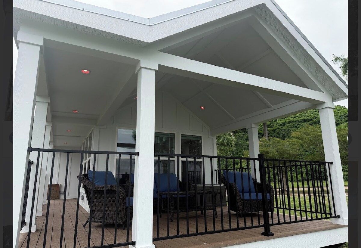 A covered outdoor seating area with wicker furniture and a black railing.