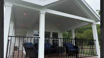 A covered outdoor seating area with wicker furniture and a black railing.