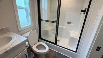 Een badkamer met toilet, bad en douchecabine.