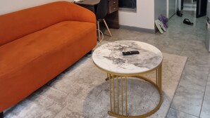 A living room with a sofa, a desk, a round coffee table, and a door leading to another room. - Modern Studio in Fedha, Nairobi (Nairobi)