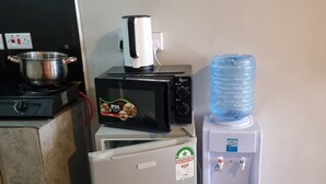 A kitchenette with a stove, microwave, refrigerator, and water dispenser. - Modern Studio in Fedha, Nairobi (Nairobi)