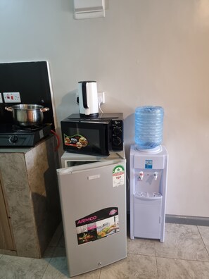 Eine Küchenzeile mit Herd, Mikrowelle, Kühlschrank und Wasserspender.
