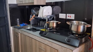 A kitchen with a stove, pots, a dish rack, and wooden cabinets. - Modern Studio in Fedha, Nairobi (Nairobi)