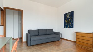 A room with a grey sofa, a wooden dresser, and a painting on the wall. - Cozy 70m2 apartment, ideal for 4 people, located on the eighth floor of a building with lift (5 steps to access it).The accommodation is located in a quiet residential area, known for its proximity to the Parco Nord Milano.Served by the Milan Affori stat (Milan)