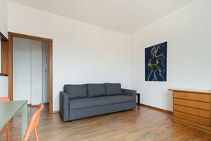 Ein Zimmer mit einem grauen Sofa, einem Holzschrank und einem Gemälde an der Wand.