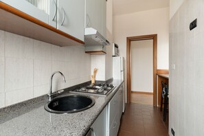 Cocina con encimera de granito, pileta de acero inoxidable y estufa a gas.
