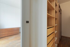 A room with a wooden floor, a white wall, and a wooden closet with shelves. - Cozy 70m2 apartment, ideal for 4 people, located on the eighth floor of a building with lift (5 steps to access it).The accommodation is located in a quiet residential area, known for its proximity to the Parco Nord Milano.Served by the Milan Affori stat (Milan)