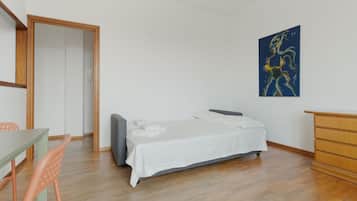 Ein Schlafzimmer mit einem Bett, einem Schreibtisch, einem Stuhl, einer Kommode und einem Bild an der Wand.