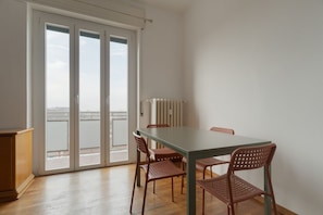 A dining area with a table and chairs, a radiator, and a view through a glass door. - Cozy 70m2 apartment, ideal for 4 people, located on the eighth floor of a building with lift (5 steps to access it).The accommodation is located in a quiet residential area, known for its proximity to the Parco Nord Milano.Served by the Milan Affori stat (Milan)