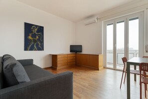 Ein modernes Wohnzimmer mit grauem Sofa, Holzschrank und Flachbildfernseher.