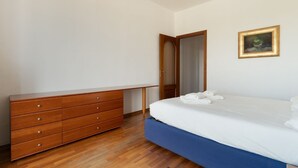 A bedroom with a wooden dresser, a bed with white bedding, and a framed picture on the wall. - Cozy 70m2 apartment, ideal for 4 people, located on the eighth floor of a building with lift (5 steps to access it).The accommodation is located in a quiet residential area, known for its proximity to the Parco Nord Milano.Served by the Milan Affori stat (Milan)