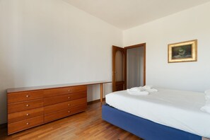 Ein Schlafzimmer mit einem Holzkasten, einem Bett mit weißer Bettwäsche und einem gerahmten Bild an der Wand.