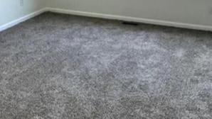 Een kamer met een groot raam, vloerbedekking en witte wanden.