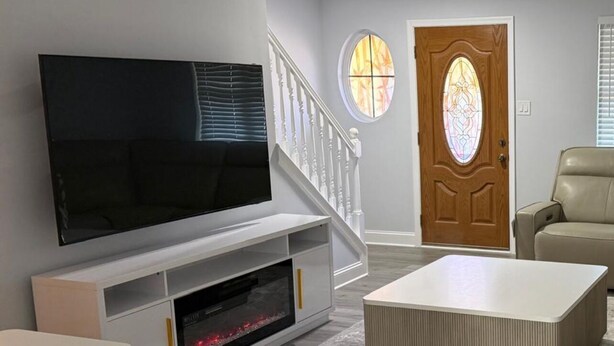 Een moderne woonkamer met een flatscreen televisie, een open haard, een trap en een deur met glas-in-lood.