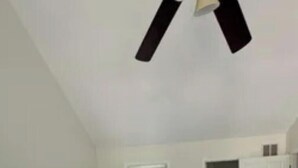Een kamer met een tapijtvloer, witte muren, een plafondventilator en een deur naar een inloopkast.