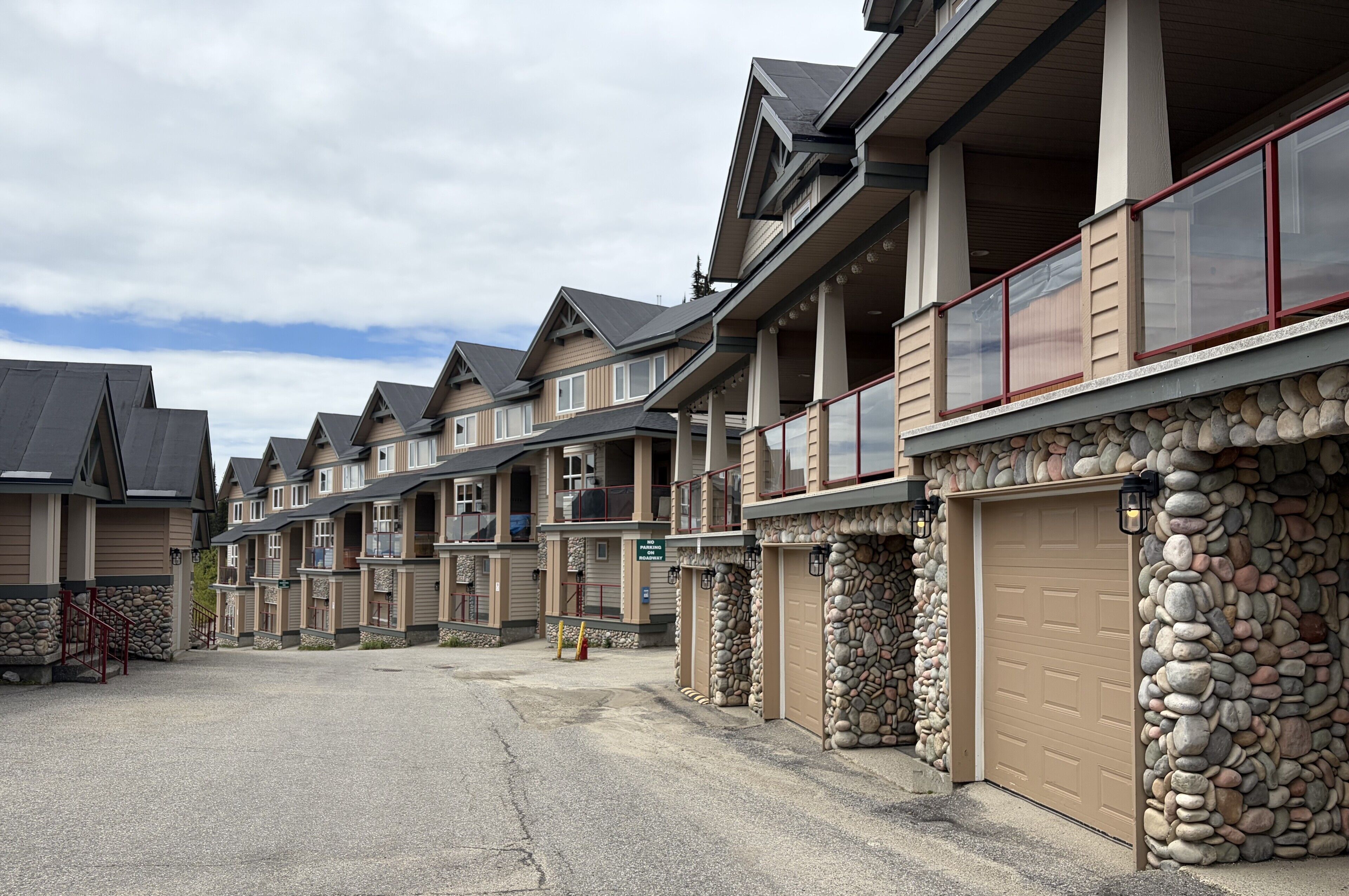 Une rangée de maisons de ville avec des murs en pierre, des balcons et des portes de garage.