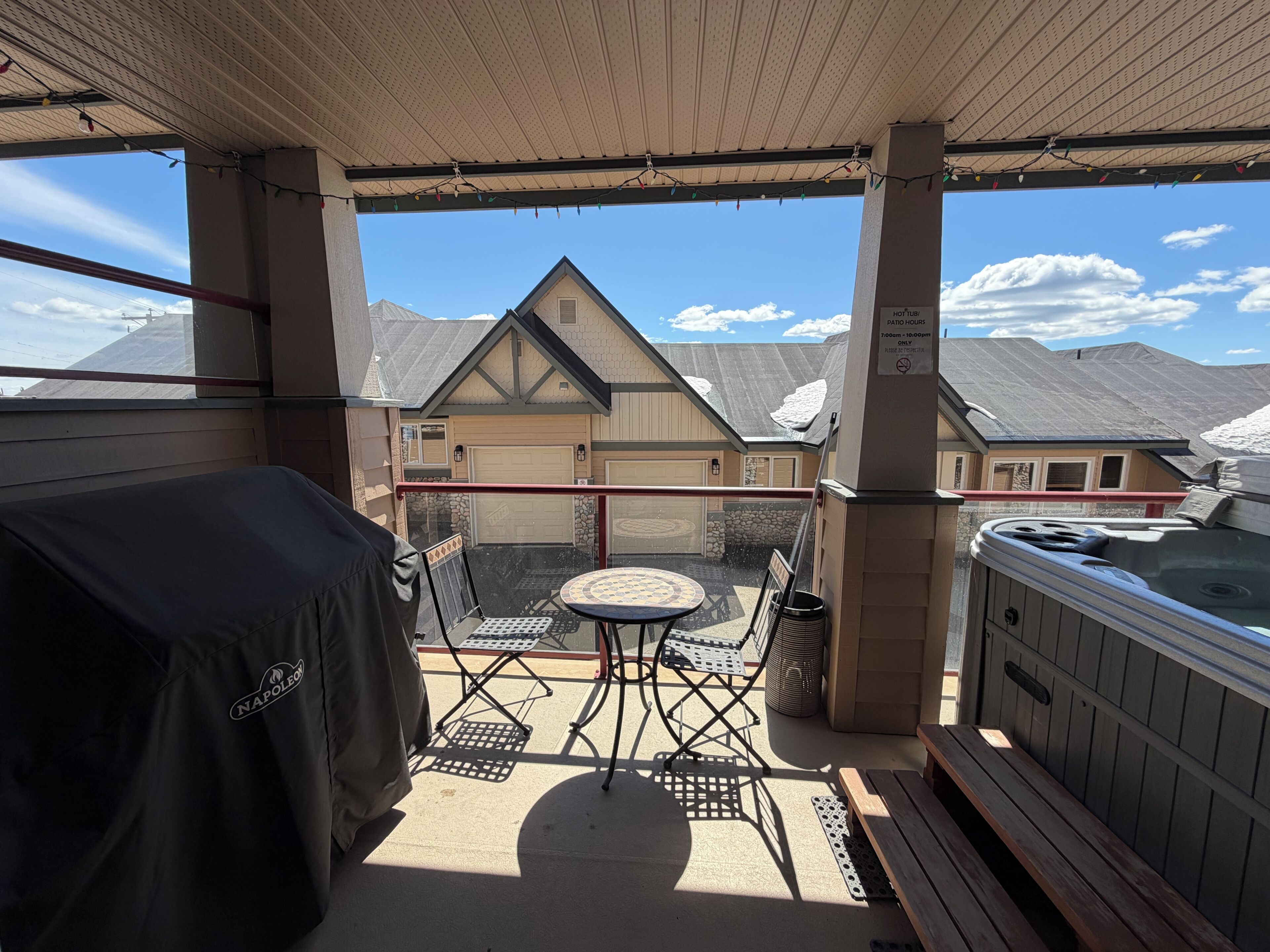 Une terrasse couverte avec un jacuzzi, une table et des chaises.