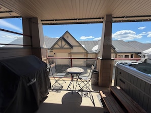 Eine überdachte Terrasse mit Whirlpool, Tisch und Stühlen.