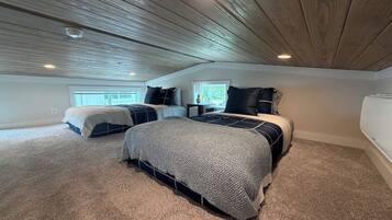 A bedroom with a sloped ceiling, a large bed, a smaller bed, and a window.