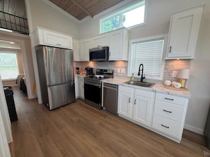 Una cocina moderna con armarios blancos, electrodomésticos de acero inoxidable y piso de madera.