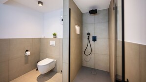 Une salle de bain moderne avec des toilettes, une douche et une petite plante en pot accrochée au mur.
