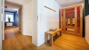 Un couloir doté d’un plancher en bois, d’un banc, d’une porte et d’un espace sauna avec des portes en verre.
