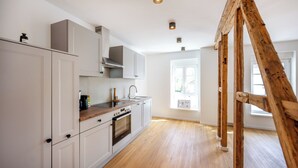 Une cuisine avec des meubles blancs, un plan de travail en bois et un four encastré.