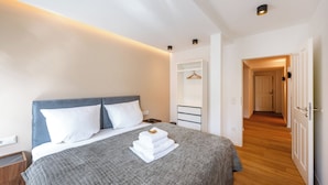 Une chambre d’hôtel comprenant un lit, une table de chevet, une armoire et un couloir menant à une autre pièce.