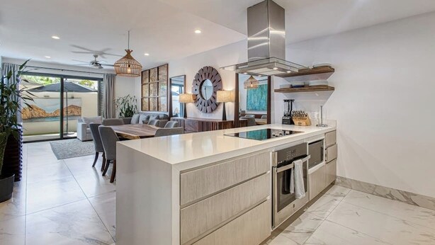 A modern kitchen with a central island, built-in oven, and stainless steel range hood. - Family-friendly Oasis With Pool and Steps From Medano Beach (Cabo San Lucas)