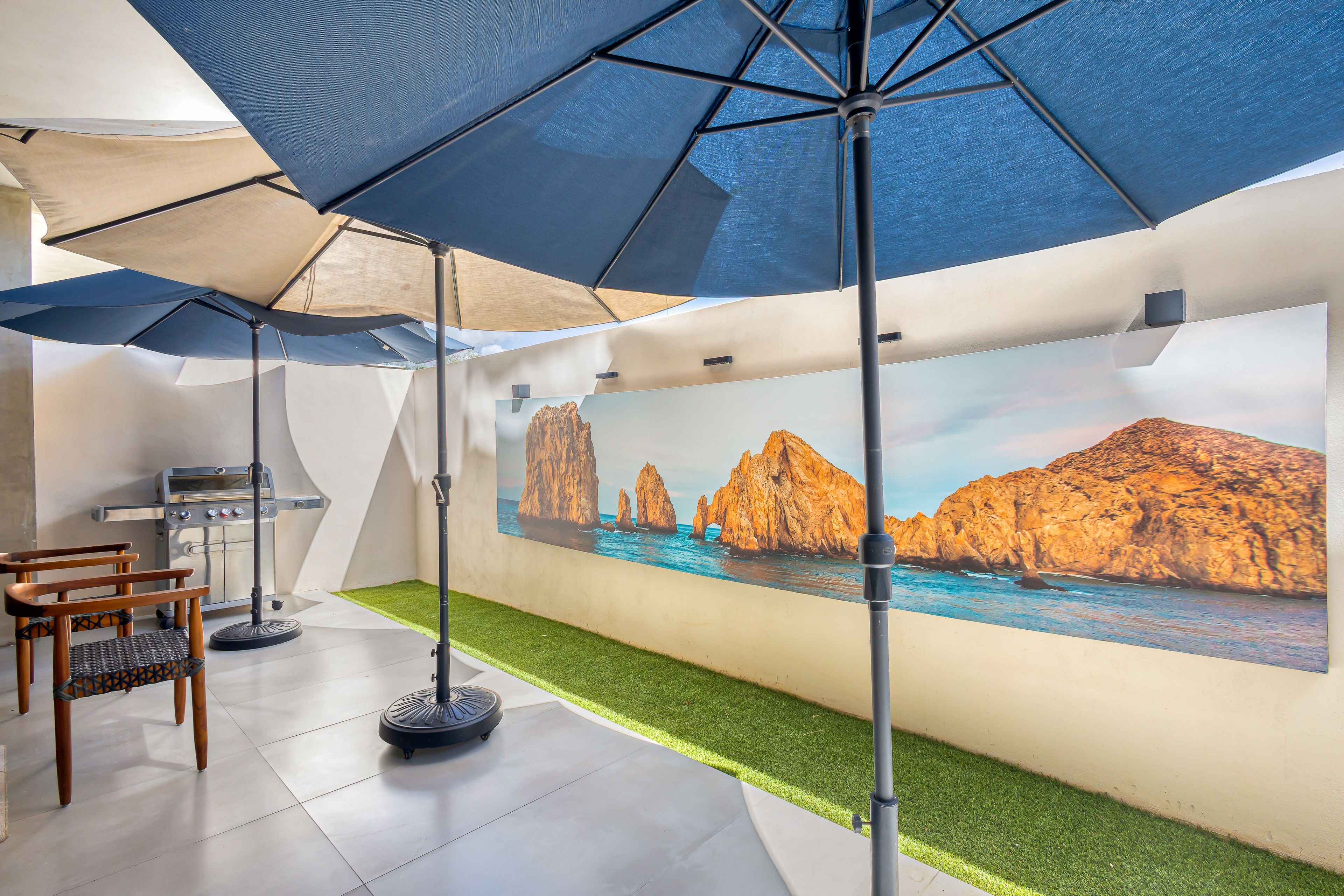 A modern interior with a dining area, a grill, and a mural of coastal rocks.