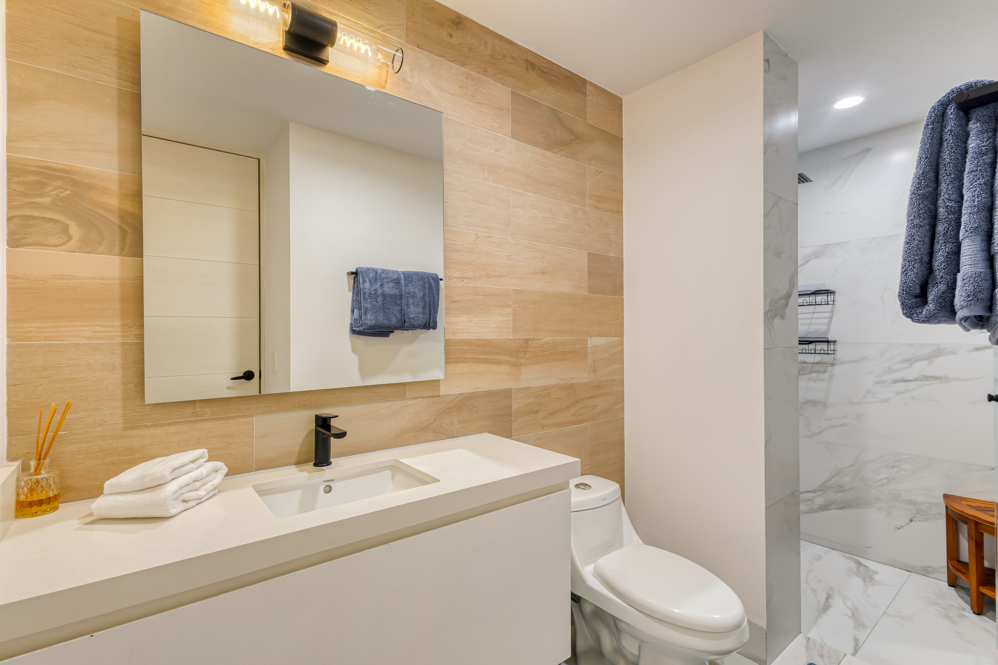 Ein modernes Badezimmer mit Waschbecken, Spiegel und Toilette in Weiß.