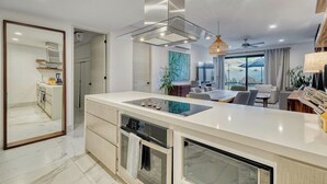 A modern kitchen with a central island, built-in oven, and a large window overlooking the sea. - Family-friendly Oasis With Pool and Steps From Medano Beach (Cabo San Lucas)