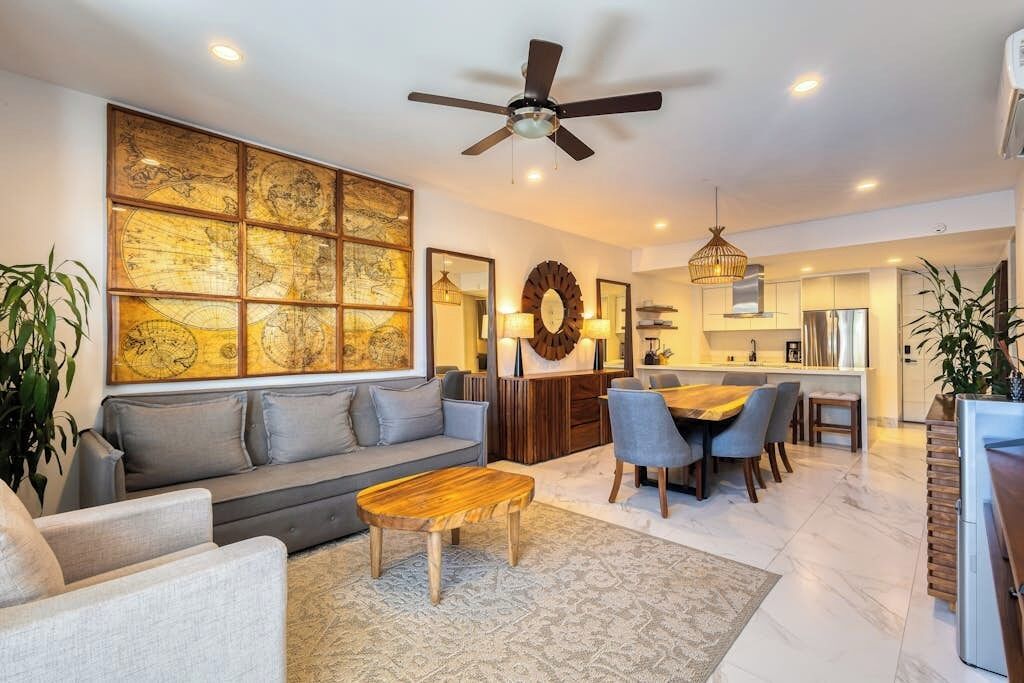 A modern living room with a sofa, coffee table, dining area, and kitchen in the background.