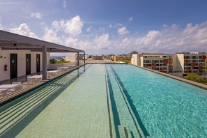Una piscina amb aigua cristal·lina, envoltada de gandules i una zona de seients coberta.
