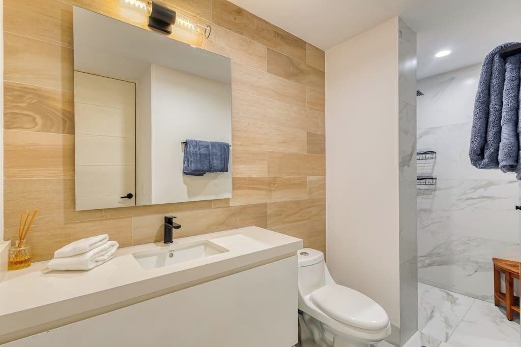 Ein modernes Badezimmer mit Waschbecken, Spiegel und Toilette in Weiß.
