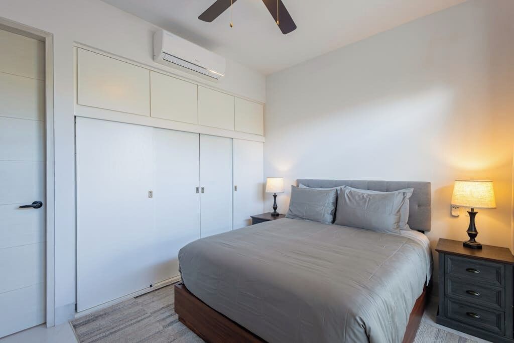 Ein Schlafzimmer mit Bett, Nachttischen, einem Kleiderschrank und einer Klimaanlage.