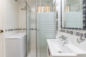Une salle de bain avec une douche à parois de verre, un lavabo blanc et un miroir doté d’un cadre décoratif.