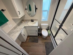 Baño con lavamanos, inodoro y zona de ducha.