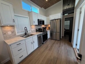 Una cocina con armarios blancos, electrodomésticos de acero inoxidable y piso de madera.