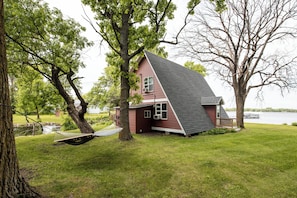 A house with a sloped roof, a hammock, and a grassy yard.