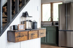 A kitchen with a coffee maker, a mug, and a 'Hello Coffee' sign on a wooden shelf.