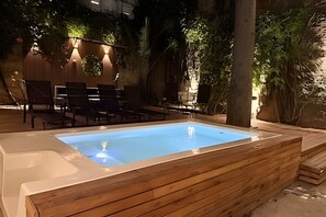An outdoor swimming pool with wooden deck seating and surrounding greenery. - House in Soho Heated Pool, BBQ Grill & Playroom (Buenos Aires)