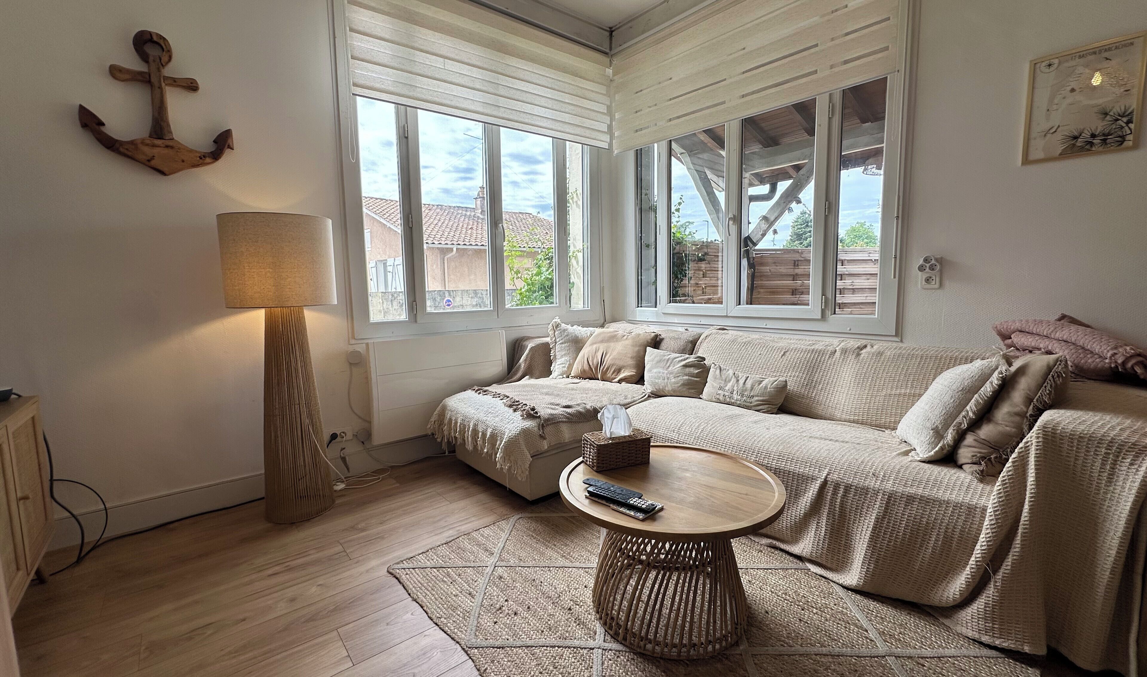 A cozy living room with a sofa, a lamp, a round coffee table, and large windows.. Apartment with a large terrace in Biganos