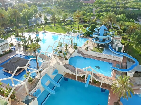 A large swimming pool with multiple slides and a water park area, surrounded by palm trees and greenery. - Apartment 'Chris' with Shared Pool, Wi-Fi, and Air Conditioning (Benalmádena)