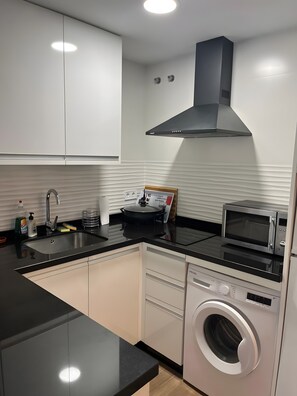 A modern kitchen with a built-in oven, microwave, sink, and a washing machine. - Apartment 'Chris' with Shared Pool, Wi-Fi, and Air Conditioning (Benalmádena)
