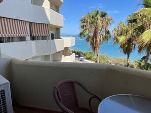 A balcony with a view of the ocean, a chair, and a table. - Apartment 'Chris' with Shared Pool, Wi-Fi, and Air Conditioning (Benalmádena)