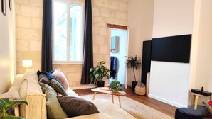 Een woonkamer met een bank, een salontafel, een televisie en een potplant.