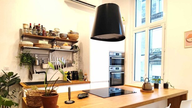 Een moderne keuken met een houten aanrecht, een zwart hanglamp en een inbouwoven.
